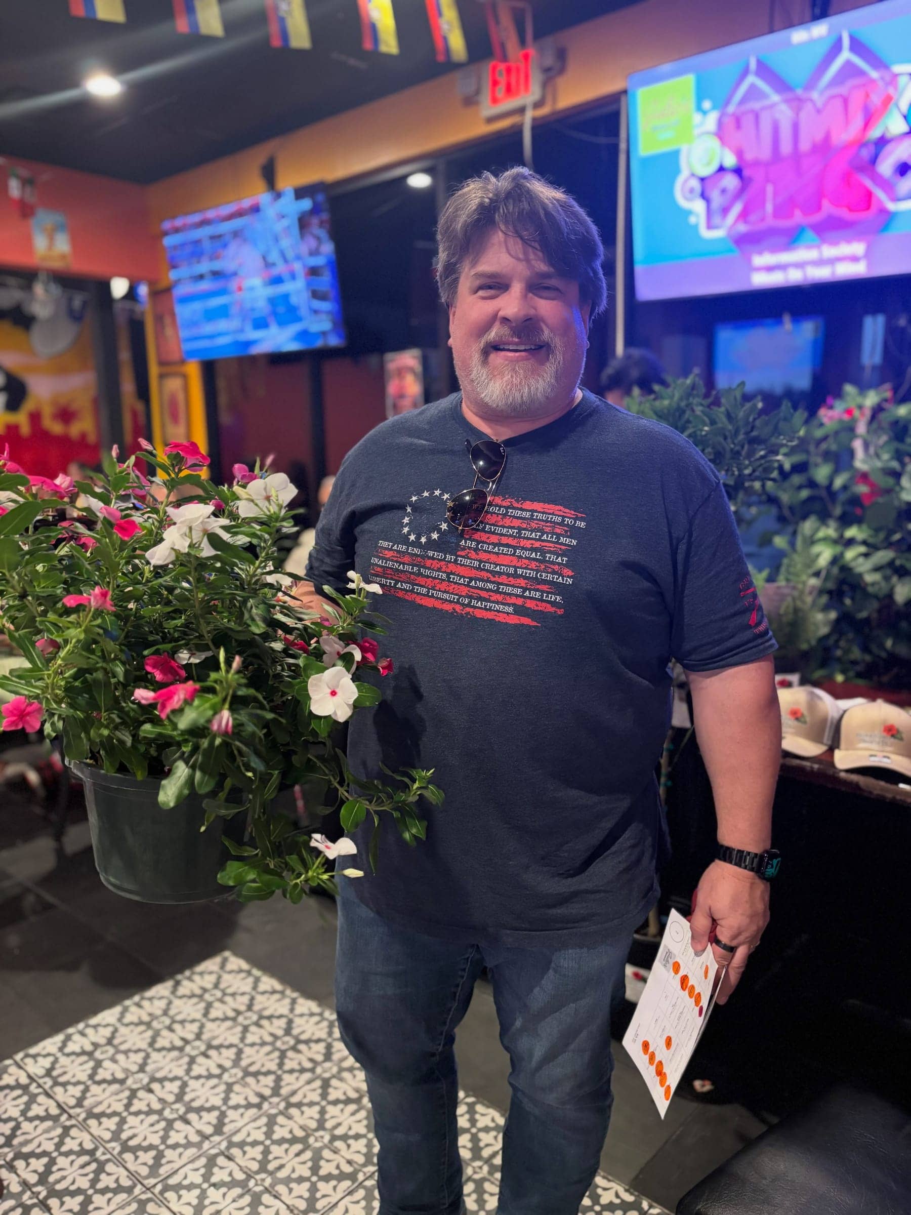 A customer holding a large pot of pink and white flowers