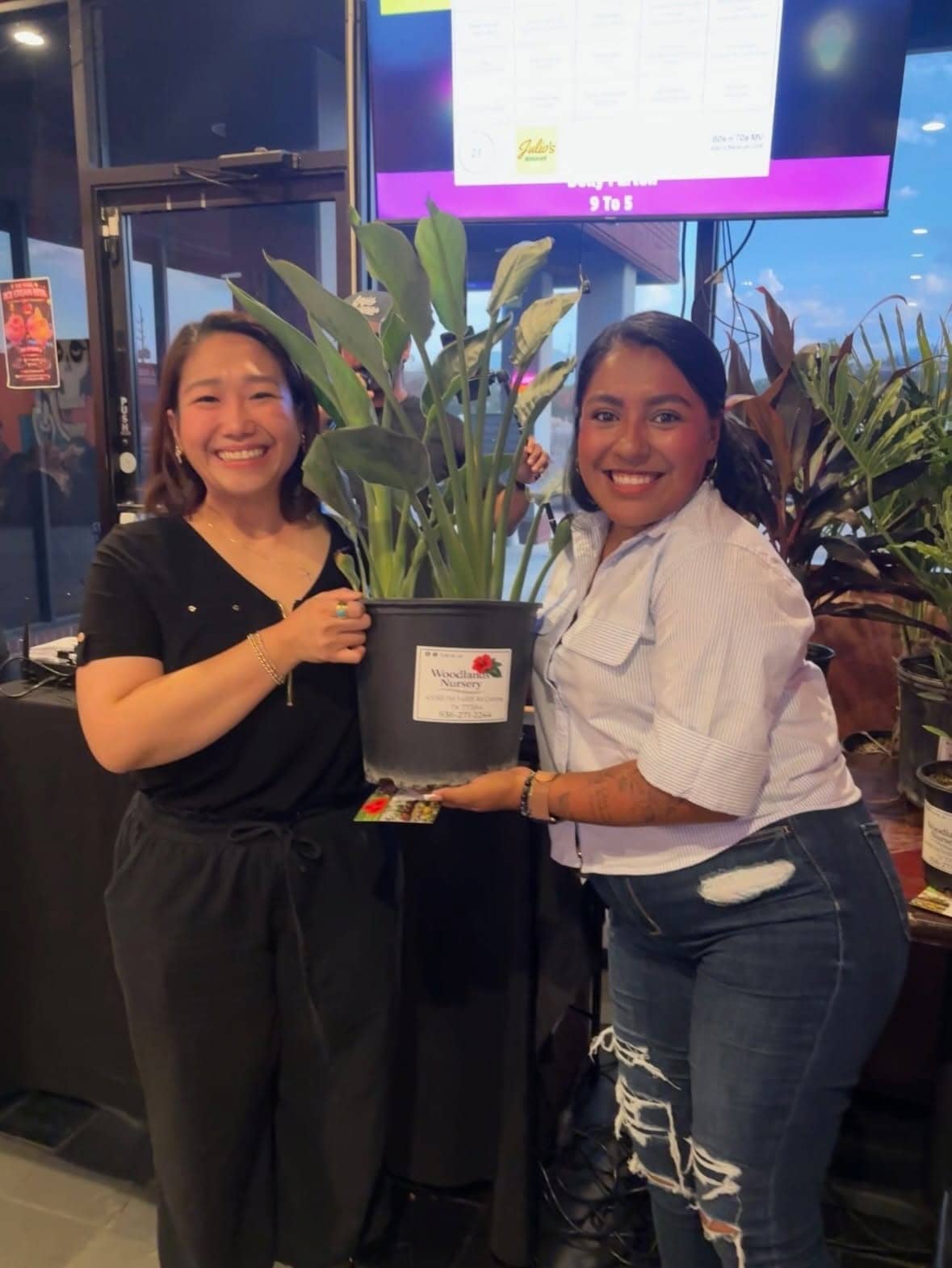Two customers holding a potted tropical plant