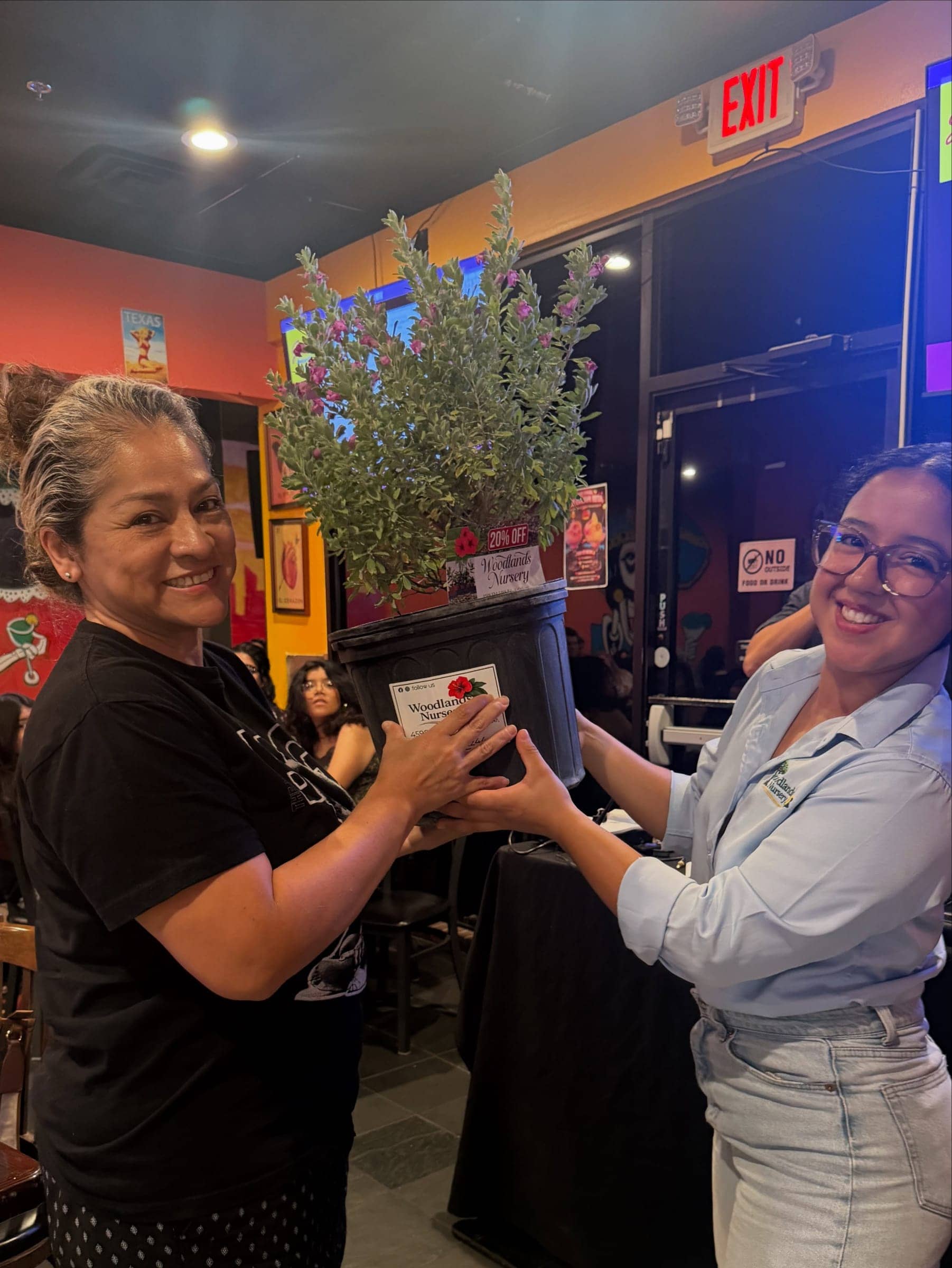 Two customers holding a flowering shrub